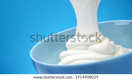 Flowing fresh greek yogurt on blue background, whipped sour cream Royalty-Free Stock Photo #1914908029