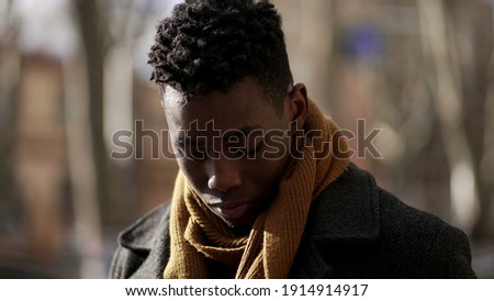 Pensive young black man standing outside thinking portrait