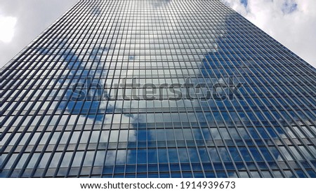 Glassy skyscraper with cloudy blue sky in the mirror reflection in Tokyo, Japan