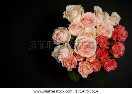 Beautiful white, red, tabby tea rose flowers in a vase, photographed from above on a black table. Spring flowers. Wedding, mother's day and valentines day background. Selective, small depth of field. 