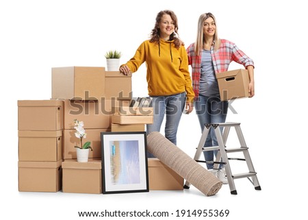 Two young female posing with a pile of cardbox boxes prepared for removal isolated on white background