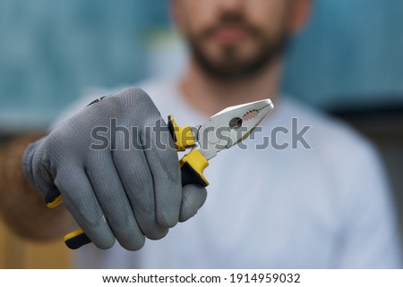 Necessary hand tool. Close up shot of hand of young repairman holding pliers Royalty-Free Stock Photo #1914959032