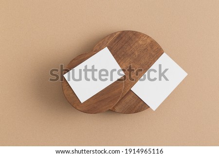 Business card on a wooden round plate against beige background. Mock up.