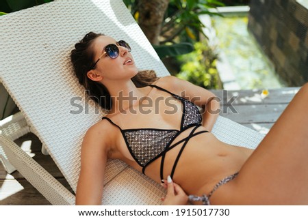 On the shisong lies a girl in sunglasses and a swimsuit in the distance pool. High quality photo