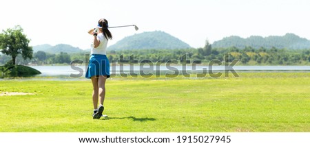 Golfer sport course golf ball fairway. People lifestyle woman playing game golf and hitting go on green grass river and mountain background.  Asia female player game shot in summer. copy space banner Royalty-Free Stock Photo #1915027945