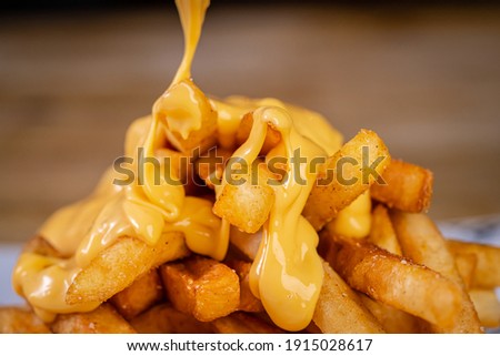 Cheddar Cheese Poured or Pulled from on top Deep Fried French Fries Royalty-Free Stock Photo #1915028617