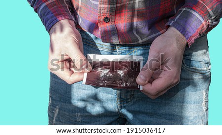 Ultrasound of a simple male in the hands of a patient is isolated on a blue background, a man looks at the history of his disease of the prostate glands, a young man with a picture of the prostate