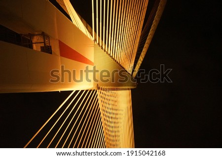 A Midnight on the bridge with the unique abstract pole of the bridge with orange color light coming from the road on it
