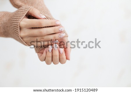 Female hand manicure close up view with warm sweater on light background.