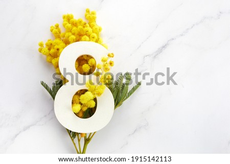 Greeting for International Women's Day on March 8th. Branches of mimosa and number eight. Royalty-Free Stock Photo #1915142113