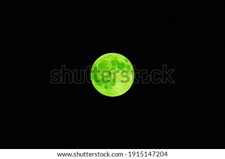 Green full moon in black night sky close up