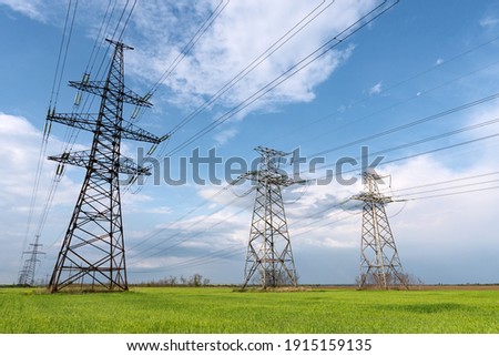 Electrical net of poles on a panorama of blue sky and green meadow. Royalty-Free Stock Photo #1915159135