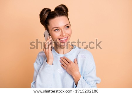 Photo of optimistic brunette lady look empty space talk telephone hand chest wear sweater isolated on pastel beige color background