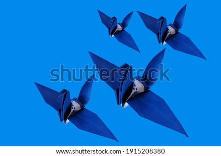 Groups Of Origami Bird Blue Colour on Pure Cyan Background. Concept of uniqueness and freedom