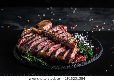 Dry Aged Barbecue Porterhouse Steak or T-bone beef steak sliced with large fillet piece with herbs and salt. banner, catering menu recipe place for text, top view. Royalty-Free Stock Photo #1915231384