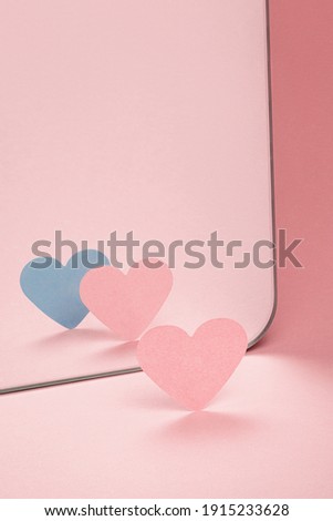 Pink paper heart in front of a mirror. Two hearts in reflection. Loneliness symbol. Lost friend. Soul in the mirror.