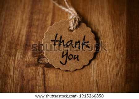 Thank you word written in a card on wooden background with selective focus. 