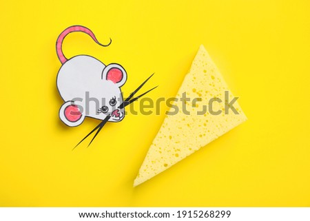 Paper mouse with piece of cheese on yellow background, flat lay