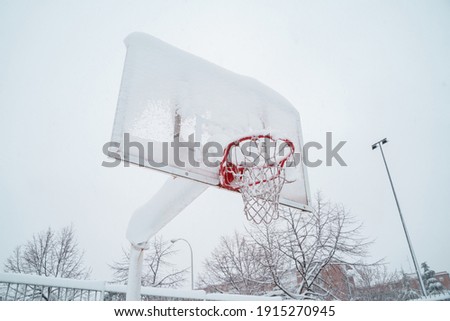 Horizontal view of frozen basketball court outdoors. Leisure in the park still not recovered from the snowstorm in Madrid in winter. Damages and insurance concept.