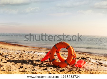 Lifebuoys and accessories on the sand of a deserted beach. Calm seascape. 