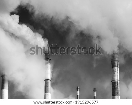 Steam comes out of the pipes of a gas thermal power plant against a blue sky, black and white