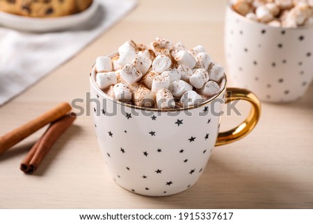 Cup of hot drink with marshmallows on wooden table