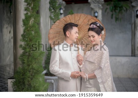 Asian couples happily take pre-wedding pictures of Valentine's Day with a Thai suit and a pink dress before getting married.