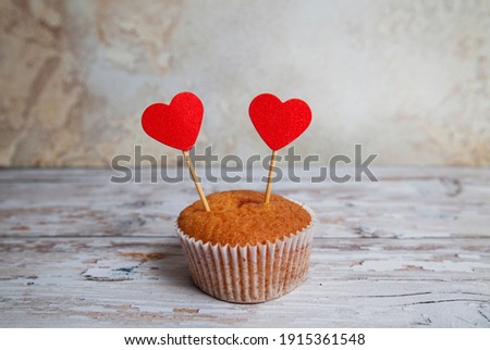 sweet cupcakes with small hearts on a skewer on a wooden background with shallow depth of field.