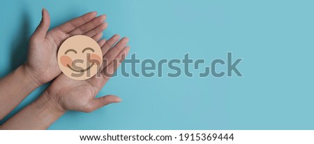 Hand holding paper cut smile face, positive thinking, mental health assessment , world mental health day concept Royalty-Free Stock Photo #1915369444