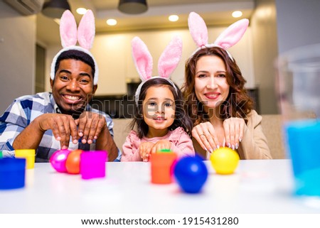 mixed race family painting eggs in cozy kitchen