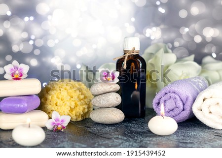 Massage stones, natural sea sponge, seashell, burning candles, rolled towels, soap, massage oil, sea salt, flowers, abstract lights. Spa resort therapy composition Soft focus
