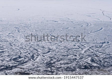 Surface of a frozen lake covered with snow and a pattern of skating tracks 