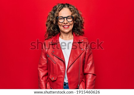 Middle age beautiful woman wearing casual red jacket and glasses over isolated background with a happy and cool smile on face. Lucky person.