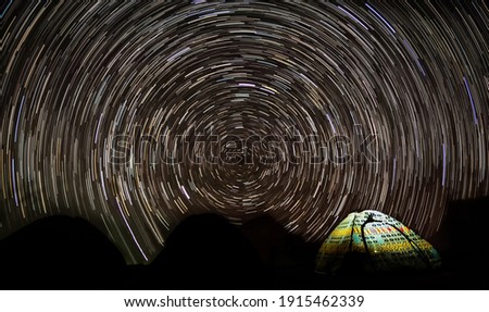 Background photo of star trail over colorful camping tent