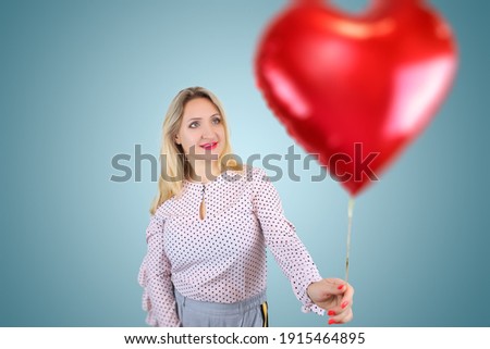 a beautiful blonde holds a heart-shaped balloon in her hands, the girl received a gift for the holiday of all lovers on the day of February 14