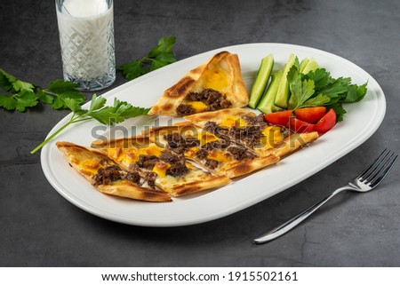 Sliced ​​cubed meat pita with buttermilk and salad on stone table.