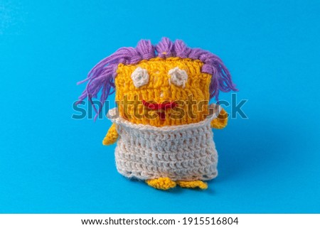Funny knitted cartoon multi-colored toy for a child. Homemade creativity and hobbies