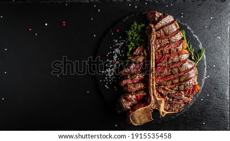 Barbecue dry aged wagyu porterhouse steak, grilled medium rare beef steak with spices served on slate board. sliced. Long banner format, top view. Royalty-Free Stock Photo #1915535458