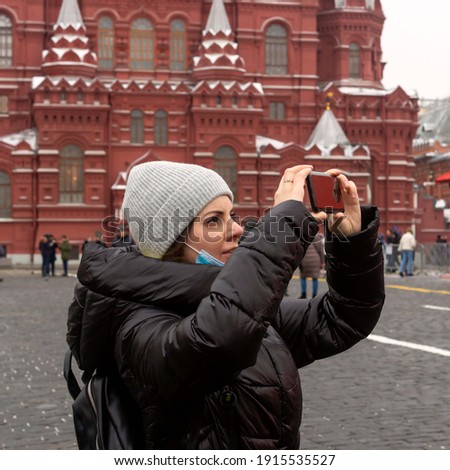 A young she tourist on Red Square in Moscow shoots architecture on a smartphone