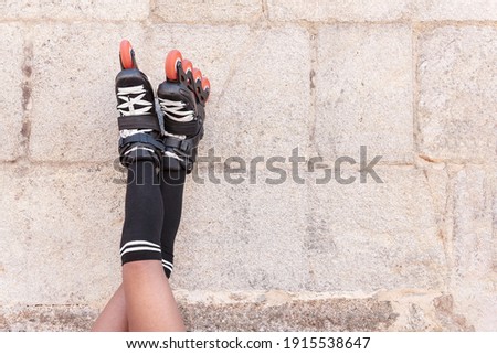 Close-up of legs up high with inline skates leaning against a stone wall resting for later training, skating outdoors and playing sports on a hot summer day
