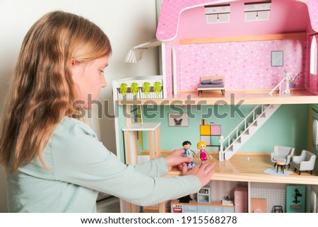 Happy girl plays with doll house and dolls. Happy child.