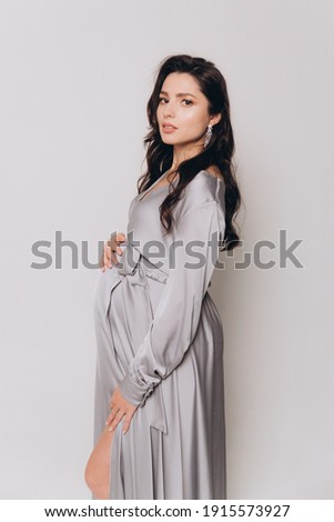Pregnancy photoshoot of a beautiful couple, future parents in a gray dress and suit