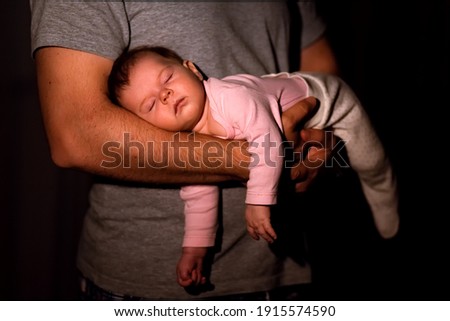 dad cradles baby in his arms at home at night by lamp light, baby sleep, baby colic. Royalty-Free Stock Photo #1915574590