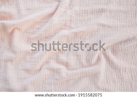 Muslin cloth texture background in neutral tones. Muslin cotton fabric of plain weave. Muslin is a soft, woven, 100-percent cotton multi-layer cloth popular for baby cloths and blankets. Royalty-Free Stock Photo #1915582075