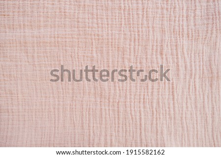 Muslin cloth texture background in neutral tones. Muslin cotton fabric of plain weave. Muslin is a soft, woven, 100-percent cotton multi-layer cloth popular for baby cloths and blankets. Royalty-Free Stock Photo #1915582162