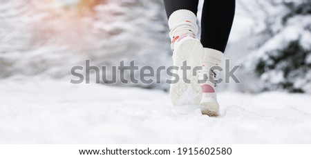 A young female athlete runs in a snowy country. Detail on sports shoes. Banner photo.