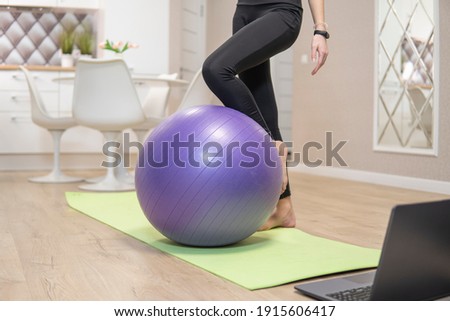 girls legs stand next to purple fitness ball. quarantine fitness concept. high quality