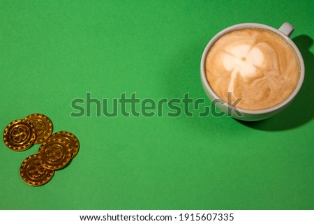 top view cappuccino cup with four leaf clover on green background