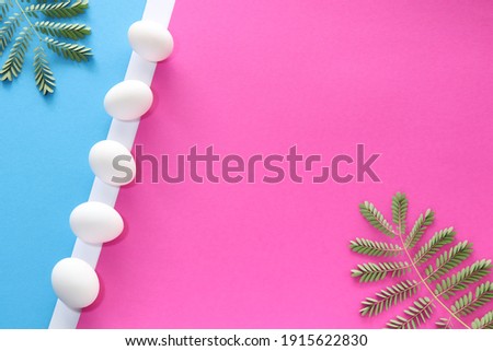 Fresh leaves in the corners with chicken eggs on white line. Pink and blue background, top view, space for text.