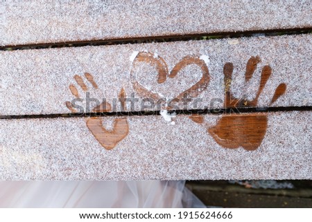 a handprint and a heart painted on the snow, two lovers drew a romantic picture on the snow in winter